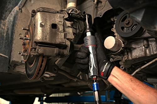 Mechanic using power tool on car brake system.