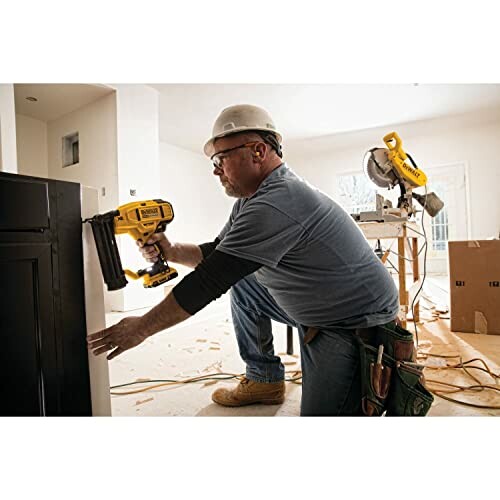 Construction worker using a nail gun on a cabinet.