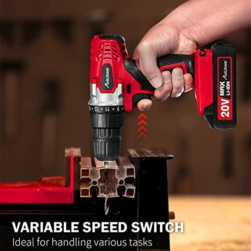 Person using a red cordless drill with a variable speed switch on metal