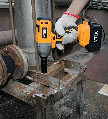 Person using cordless impact wrench on metal structure