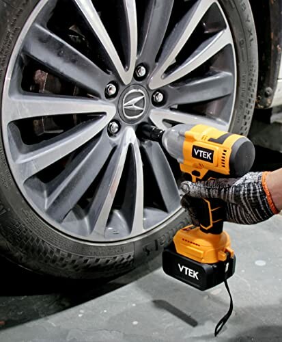 Impact wrench being used to tighten a car wheel.