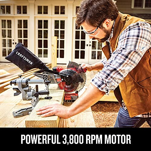 Man using a miter saw on a wooden plank outdoors.