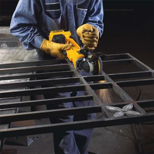 Worker using an angle grinder on metal frame