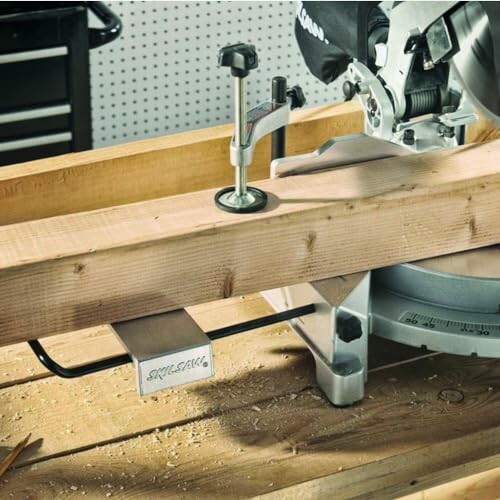 Miter saw cutting a wooden plank on a workbench.