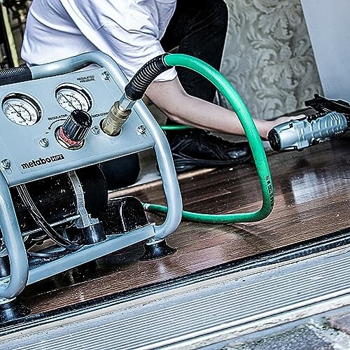 Person using a portable air compressor with a green hose.