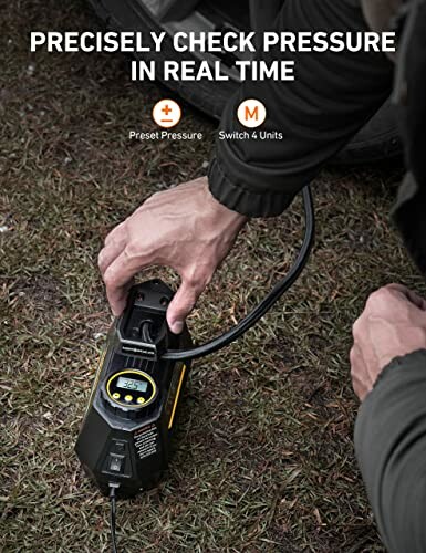 Person using a digital tire pressure gauge on a grassy surface.