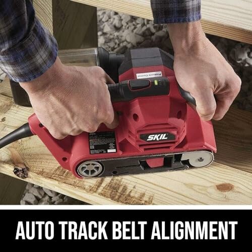 Person using a red belt sander on wood plank