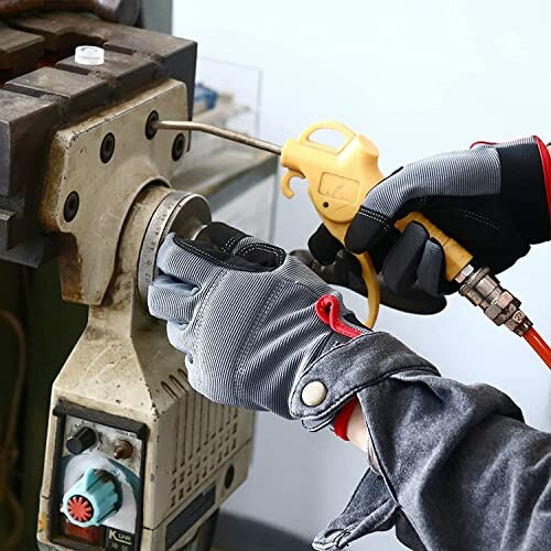 Person using an air blower tool on machinery.