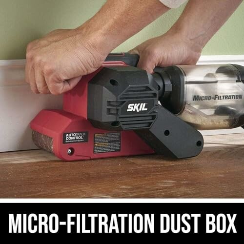 Person using SKIL belt sander with micro-filtration dust box on wooden surface.